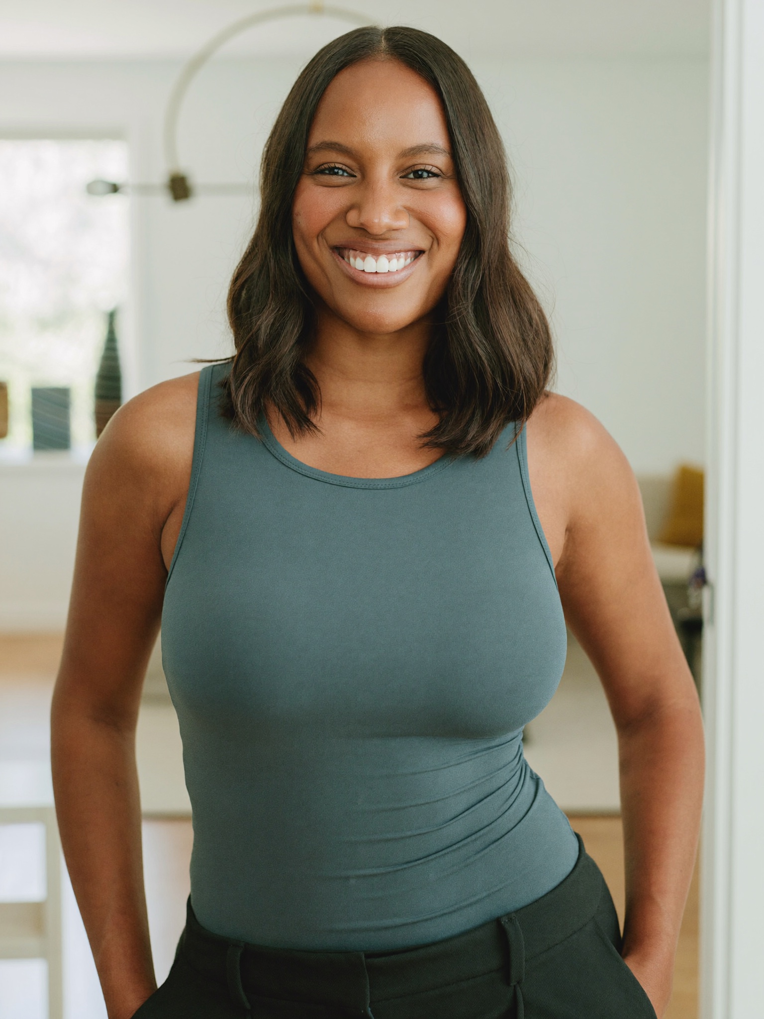 A confident woman in a fitted sleeveless top, at ease in a bright modern home after a major weight-loss transformation