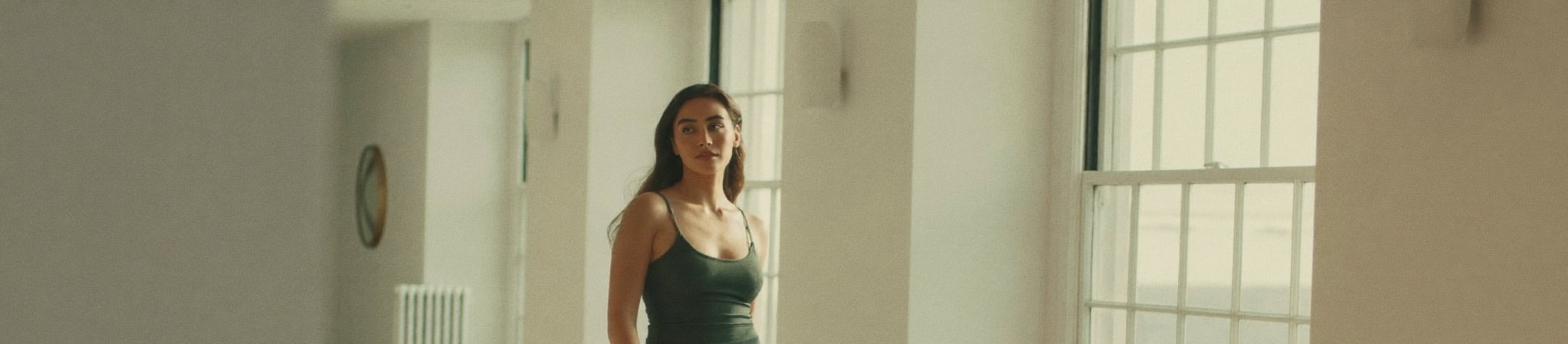 A self-assured woman in a stylish sleeveless outfit moving confidently through a bright modern space