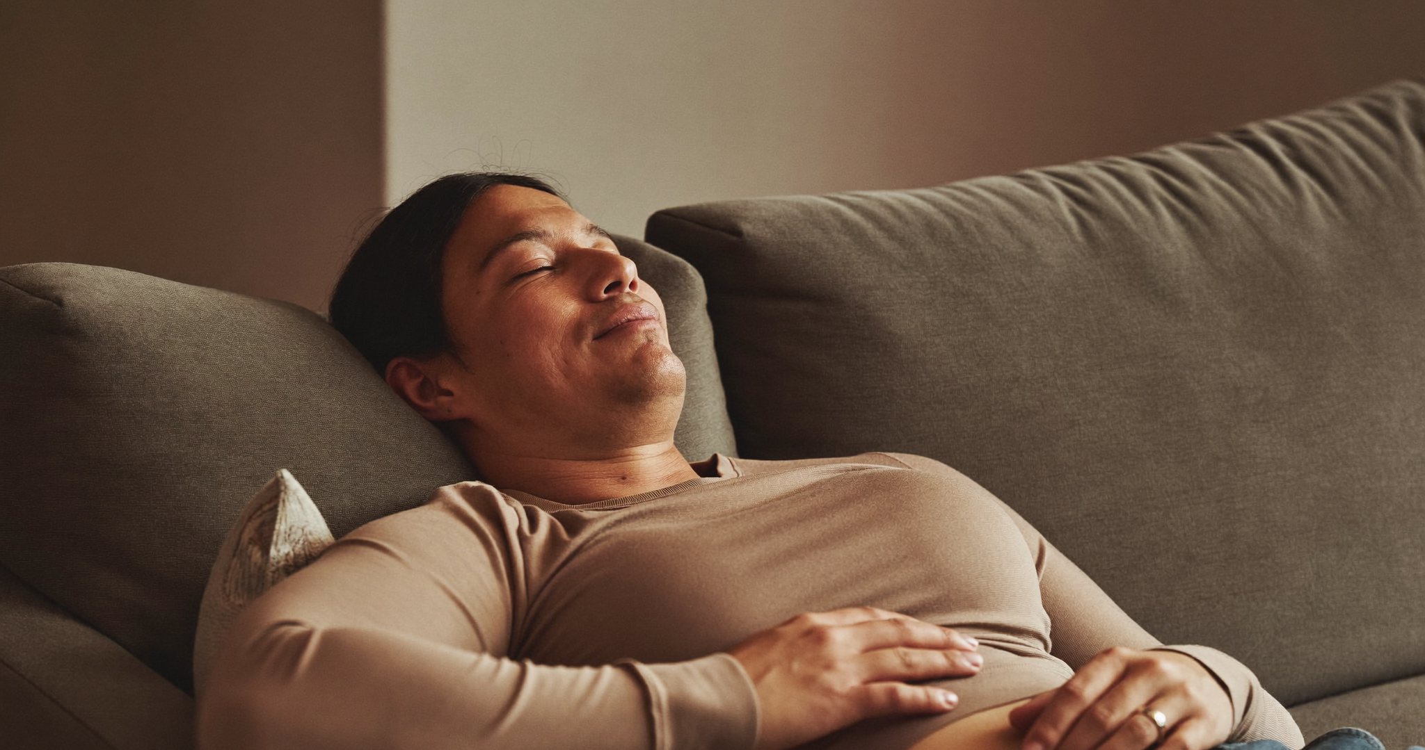 An adult resting comfortably at home during recovery, fully clothed in a soft long-sleeve top, calm and reassured