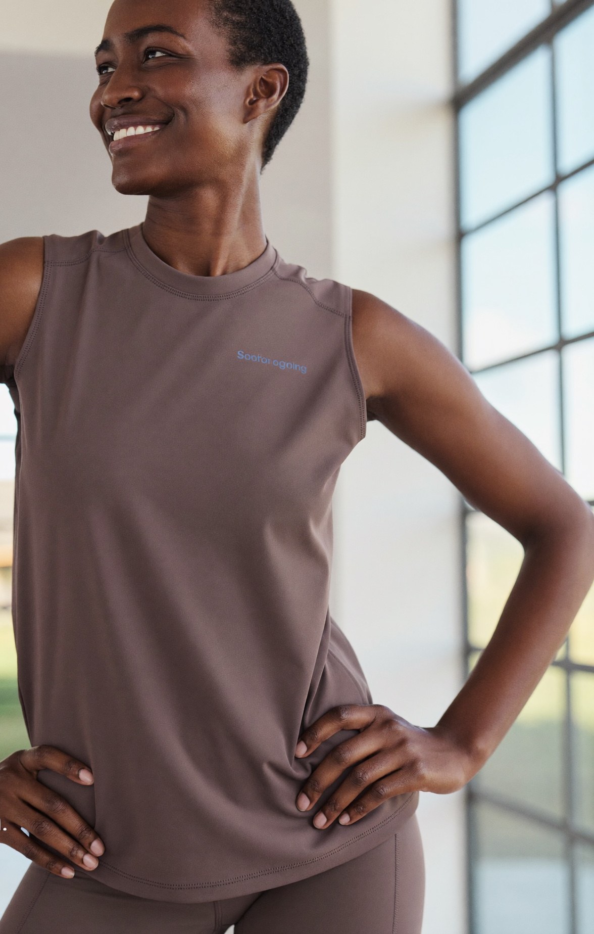 A confident adult in a fitted sleeveless top, at ease in a bright modern space after a major weight-loss journey
